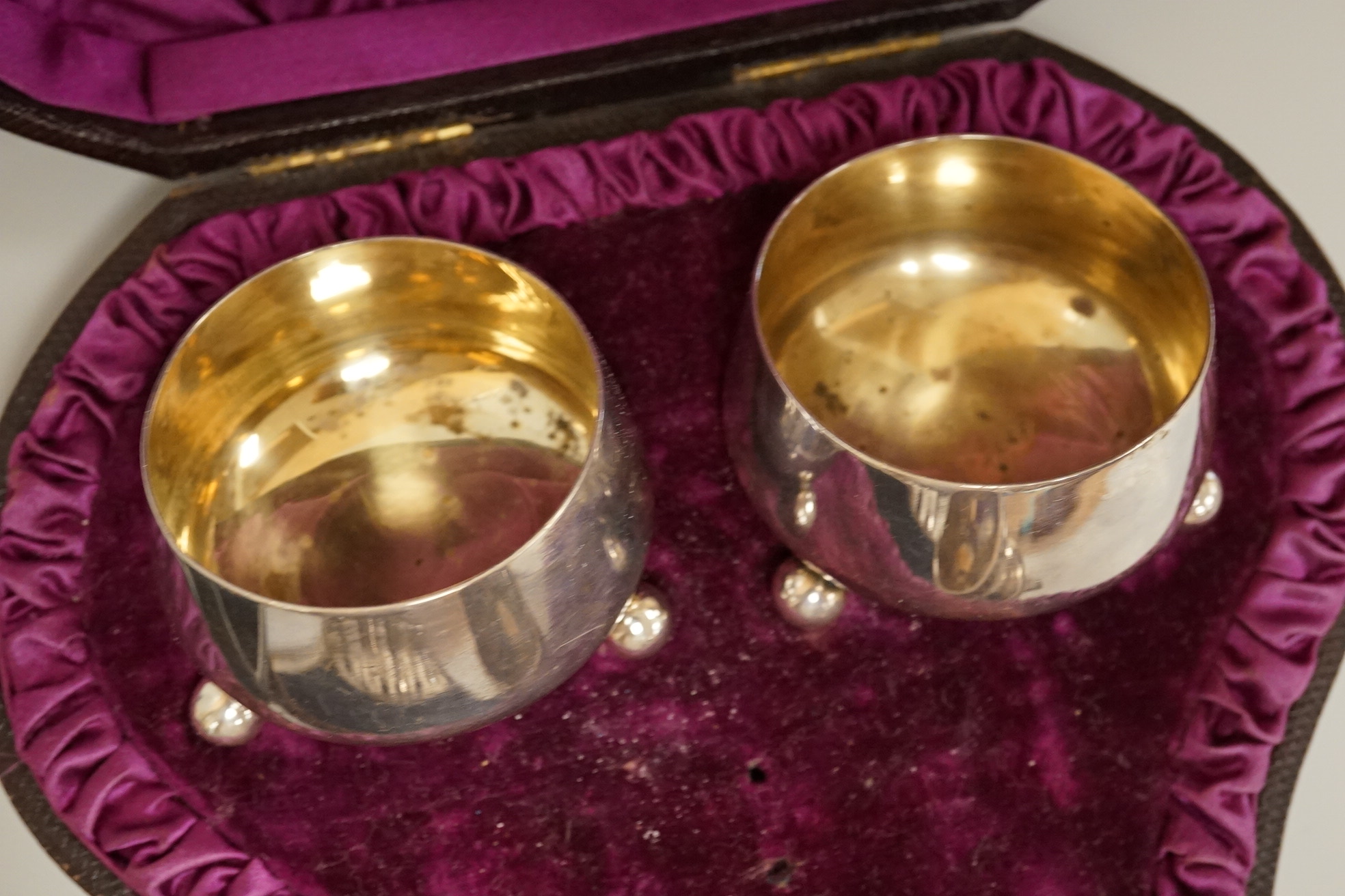 A cased pair of Victorian silver circular salts, by Edward Hutton, London, 1886, lacking spoons, together with a cased set of six silver bean end coffee spoons, a cased silver spoon, a small silver 'Dunlop Golf Ball Hole